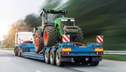 A Blue Lowboy Trailer Hauling a Farming Tractor on the Highway What Is the Lifespan of a Trailer