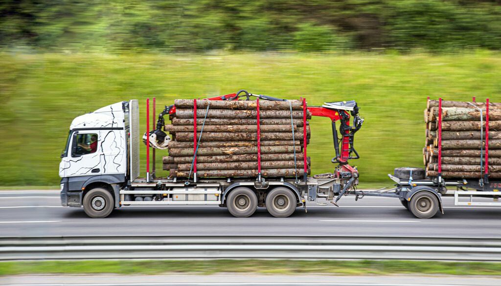 A logging trailer moving down the highway and what type of logging trailer is right for you